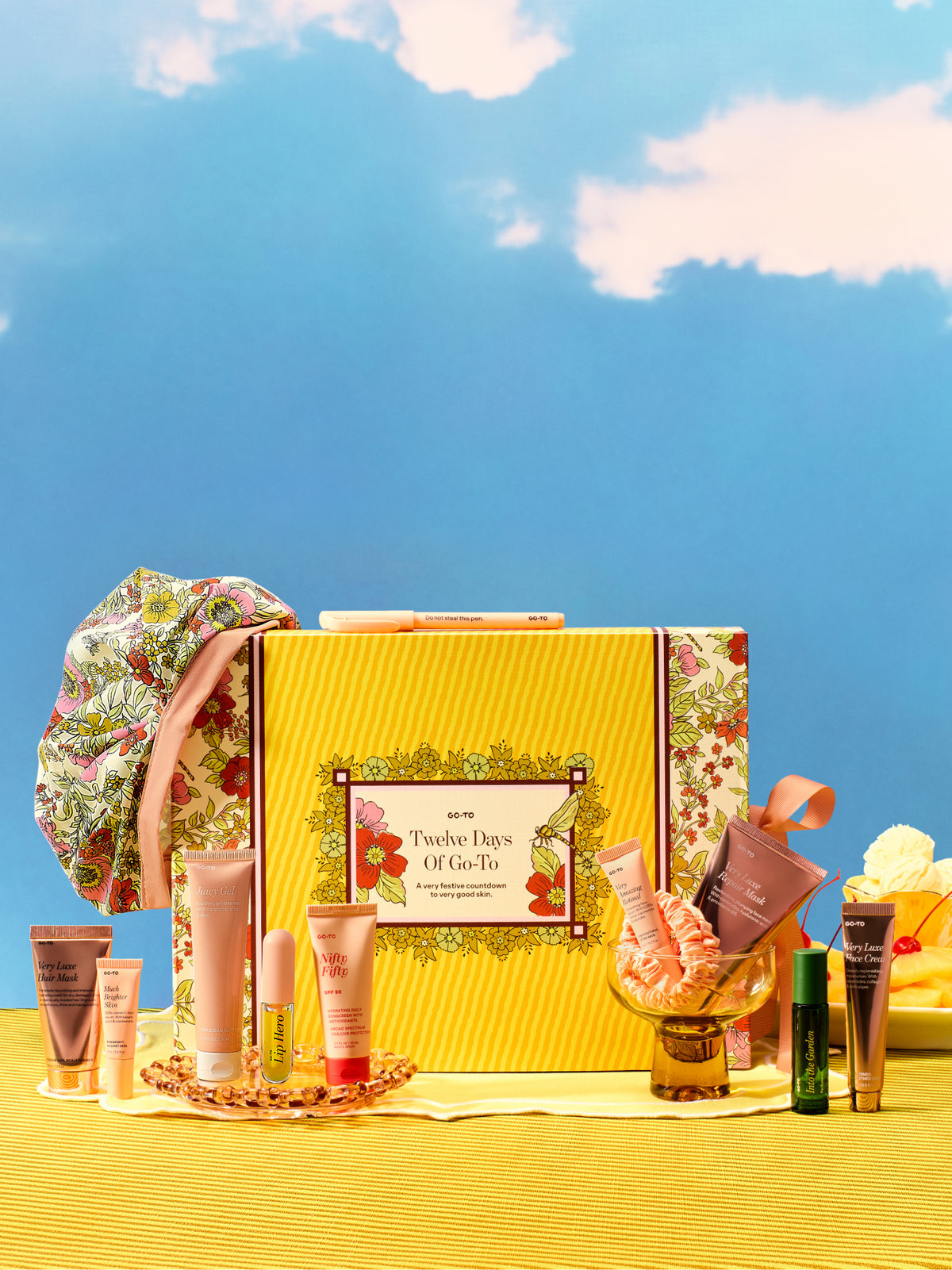 Go-To Skincare Twelve Days Of Go-To advent calendar with yellow floral packaging and an assortment of festive skincare products arranged on a bright yellow table surface