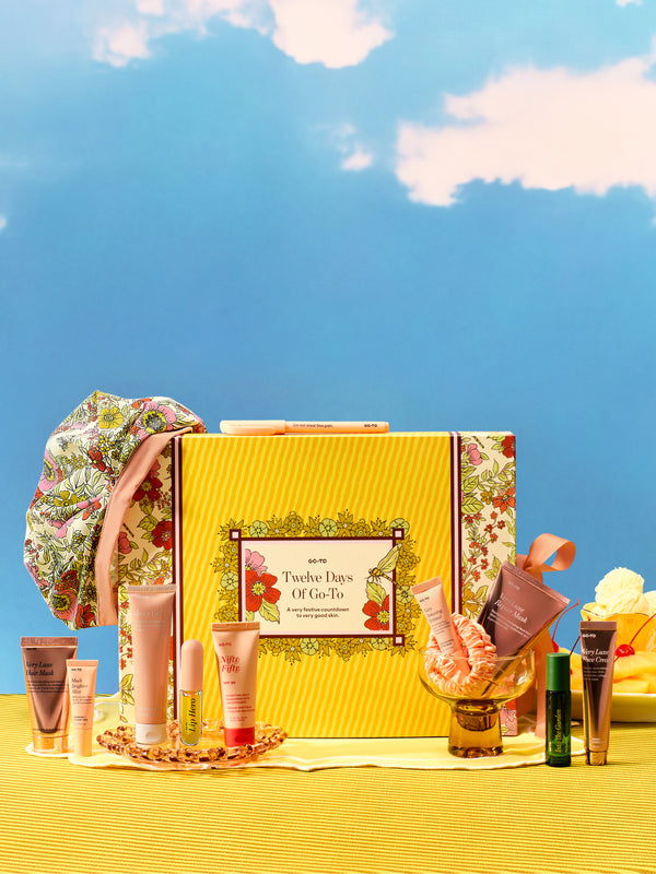 Go-To Skincare Twelve Days Of Go-To advent calendar with yellow floral packaging and an assortment of festive skincare products arranged on a bright yellow table surface