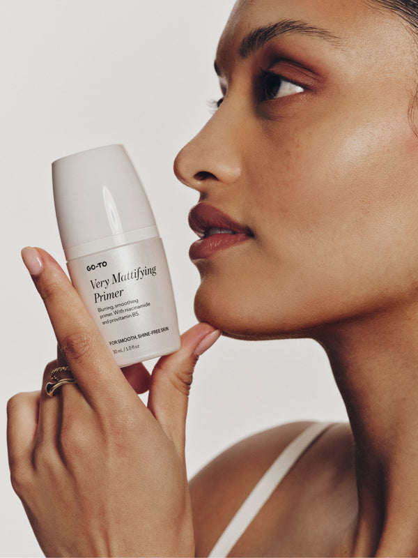 Model holding Go-To Very Mattifying Primer against smooth, shine-free skin to demonstrate blurring and smoothing results.